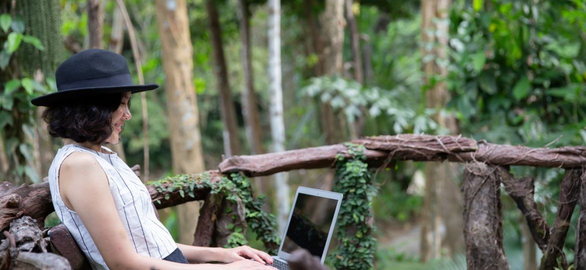 Happy woman using laptop in the forest.